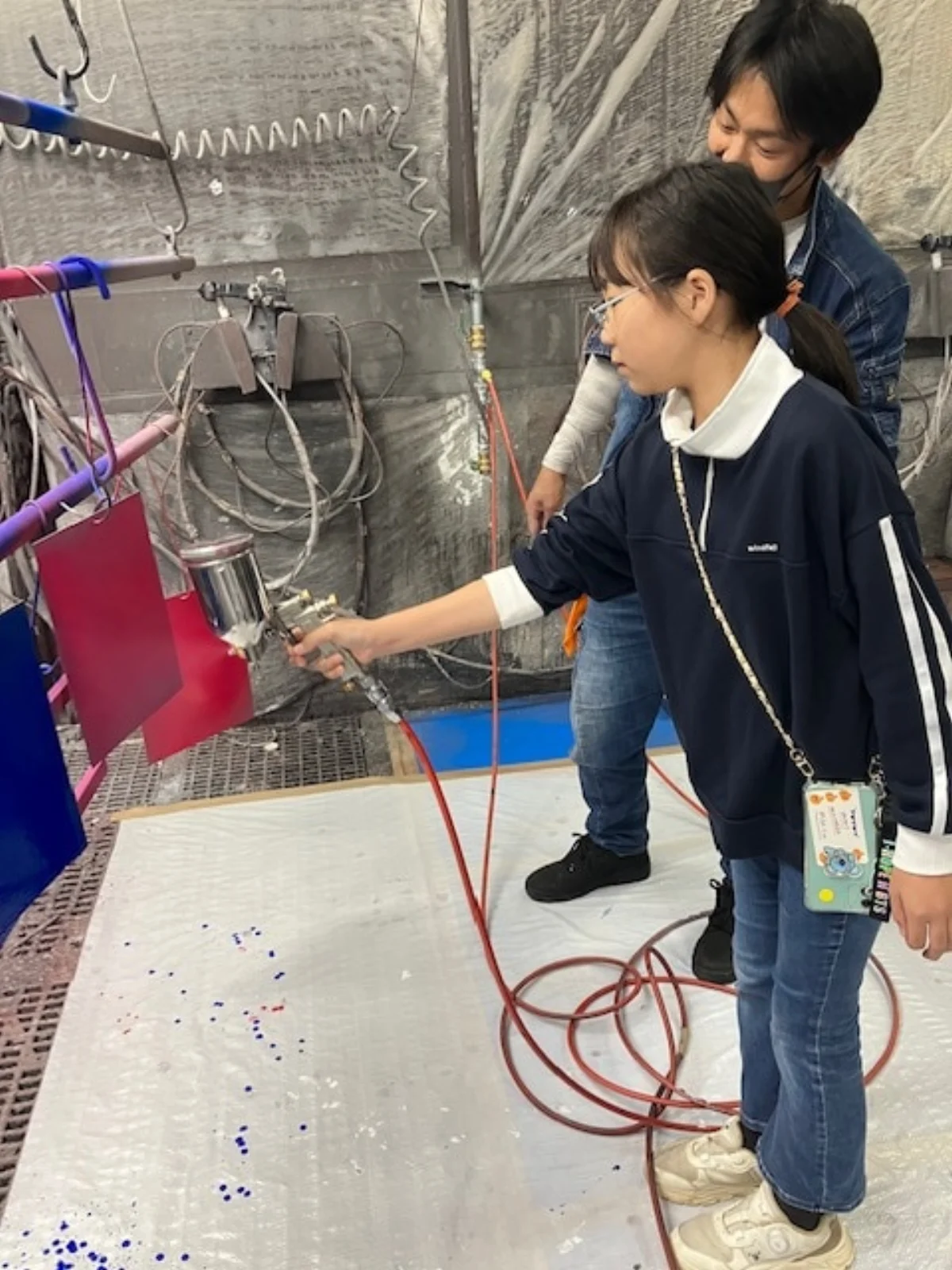 子どもがスプレーガンで塗装を体験する様子