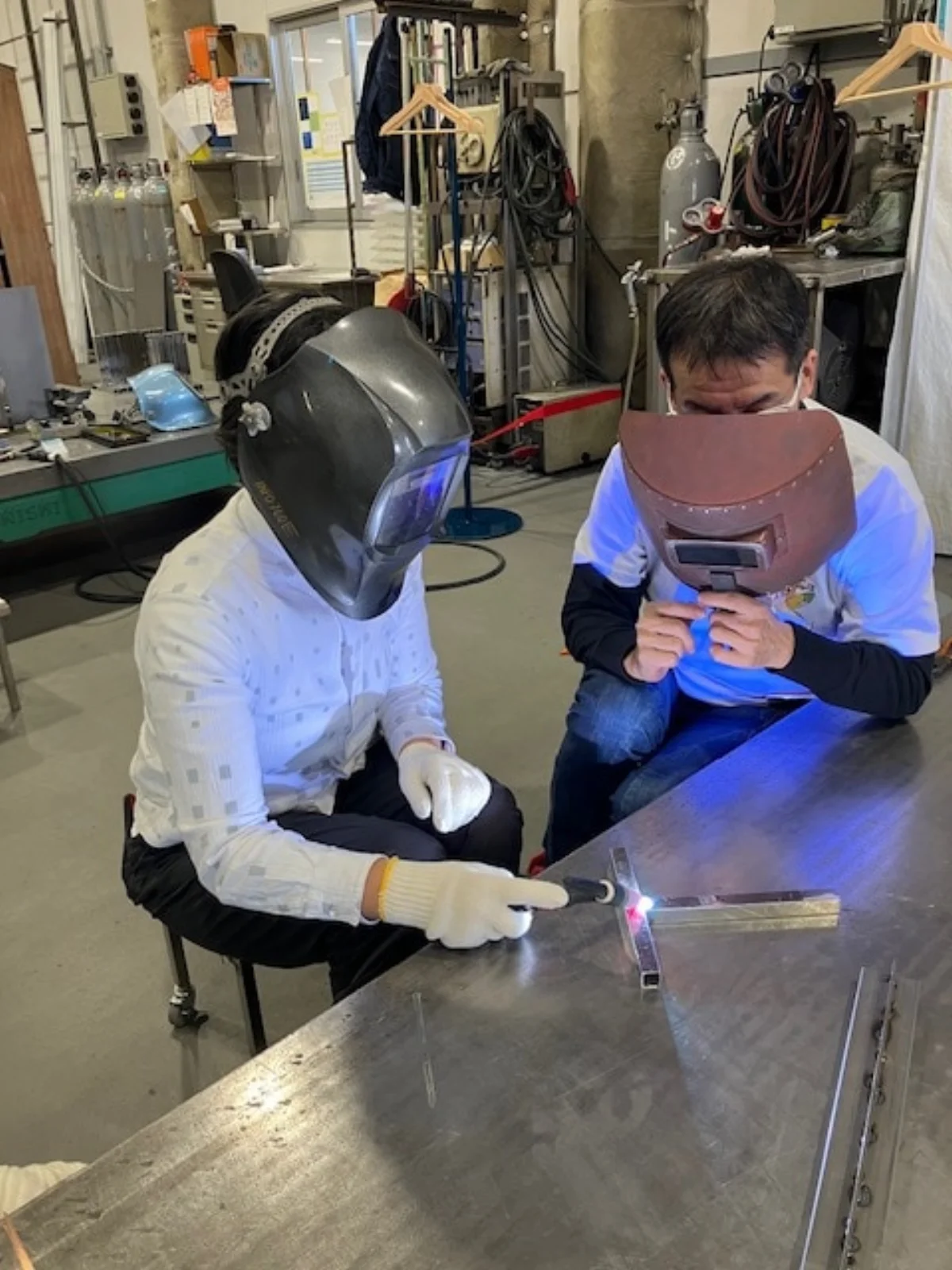 社員に教わって溶接を体験する見学者